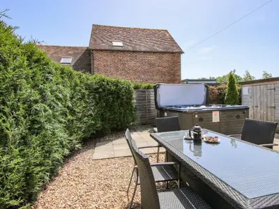 a patio with a table and chairs and a grill at The Wain House in Acton Scott