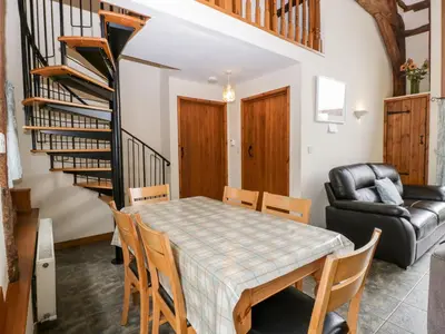 a dining room with a table and chairs and a staircase at Tippets View in Pembridge