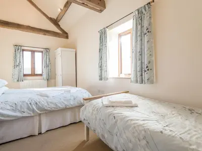 a bedroom with two beds and two windows at Glebe Barn in Caynham