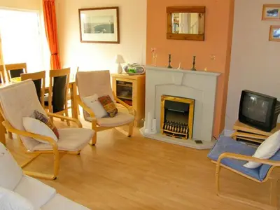 a living room with a fireplace and chairs and a tv at Trem y Mor in Harlech
