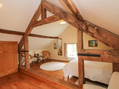 a bedroom with a bed and a wooden floor at Old Coach House in Shrawardine
