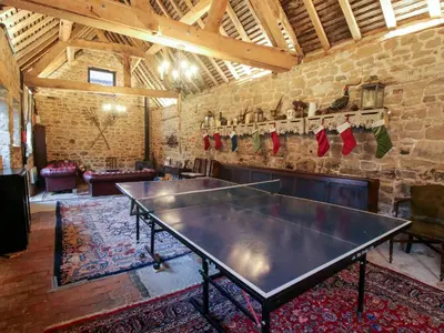 a ping pong table in a room with a brick wall at The Olde Cow House in Hughley
