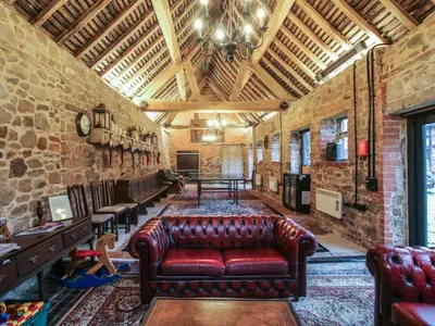 a living room with a leather couch in a brick wall at The Olde Cow House in Hughley