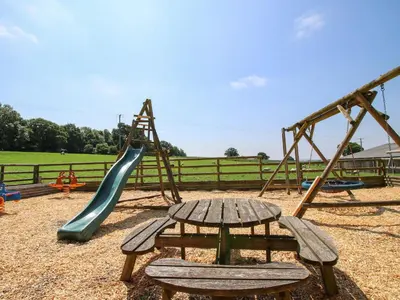 a playground with a slide and a table and a swing at The Olde Cow House in Hughley