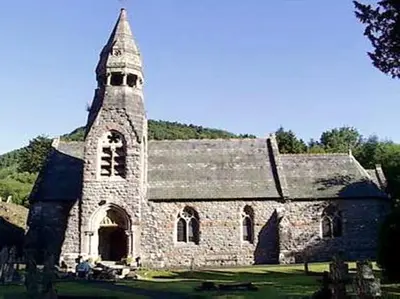 an old stone church with a tower on a field at Happy Union Stables in Abbey-Cwmhir