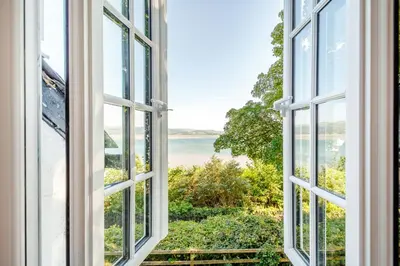 an open window with a view of the ocean at Braich-Y-Celyn Lodge in Aberdyfi
