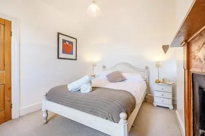 a bedroom with a white bed and a fireplace at Braich-Y-Celyn Lodge in Aberdyfi
