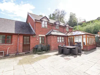 a brick house with a patio with a table and chairs at 1 The Beeches in Llangollen