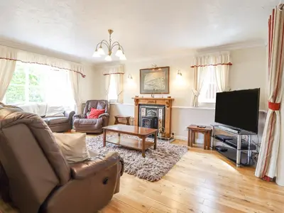a living room with a couch a television and a table at 1 The Beeches in Llangollen