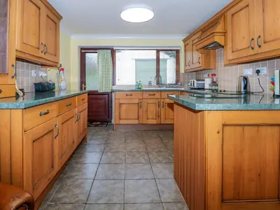 a large kitchen with wooden cabinets and granite counter tops at Brynteg in Llwyngwril