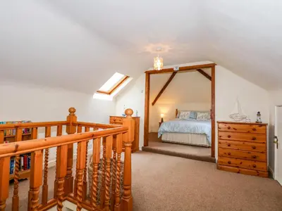 a bedroom with a bed and a wooden staircase at Brynteg in Llwyngwril