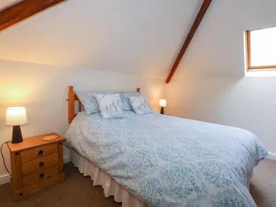 a bedroom with a bed with a blue comforter at Brynteg in Llwyngwril