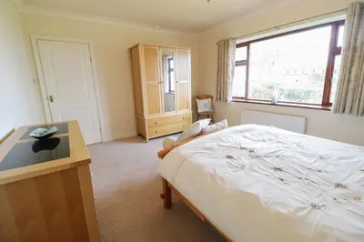 a bedroom with a bed and a desk and a window at Brynteg in Llwyngwril