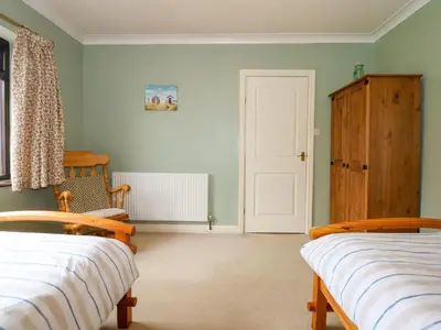 a bedroom with two beds and a door at Brynteg in Llwyngwril