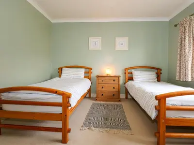 two twin beds in a room with a dresser at Brynteg in Llwyngwril