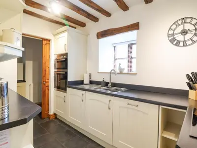 a kitchen with white cabinets and a clock on the wall at Isallt in Llanbedr