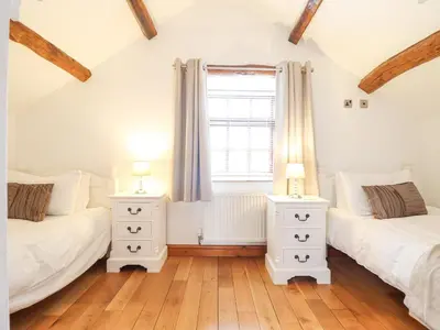 two beds in a room with a window and two lamps at Isallt in Llanbedr