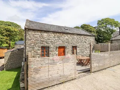a stone cottage with a wooden fence in front of it at Isallt in Llanbedr