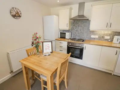 a kitchen with a wooden table and a kitchen with white cabinets at Kite's Nest in Eaton