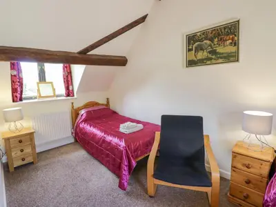 a small bedroom with a bed and a chair at Betty's Barn in Eaton