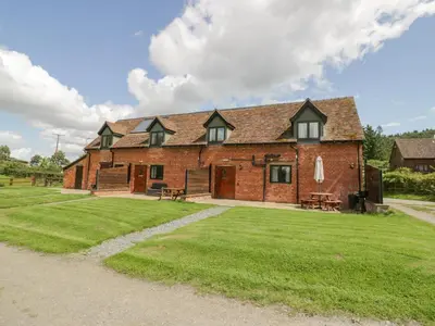 a large brick building on a grass field at Betty's Barn in Eaton