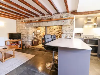 a kitchen with a counter and a stone wall at Cwm Yr Afon Cottage in Harlech