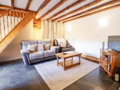a living room with a couch and a table at Cwm Yr Afon Cottage in Harlech