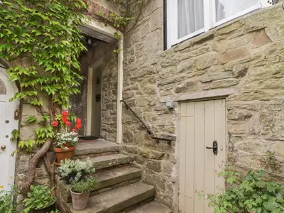 a stone house with a white door and flowers at The School Room in Kington