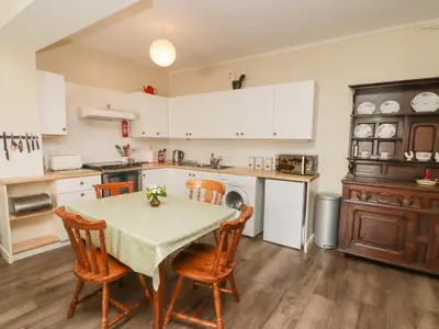 a kitchen with a table and chairs and a kitchen with white cabinets at The School Room in Kington