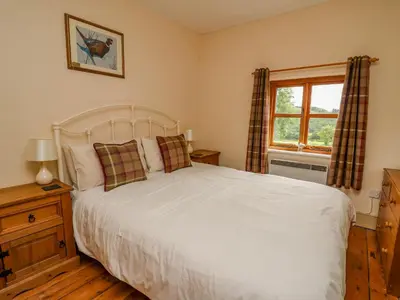 a bedroom with a white bed and a window at Byrdir Cottage in Llanwrthwl