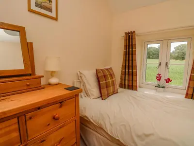 a bedroom with a bed and a dresser and a mirror at Byrdir Cottage in Llanwrthwl