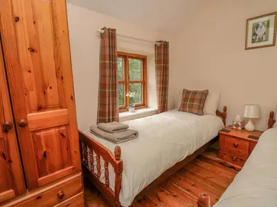 a bedroom with two beds and a window at Byrdir Cottage in Llanwrthwl
