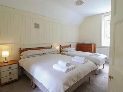 two beds in a bedroom with white sheets and towels at Bryn Cemlyn in Llanfachreth