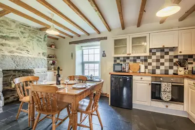 a kitchen with a wooden table and chairs at Ty Capel Jeriwsalem in Trawsfynydd
