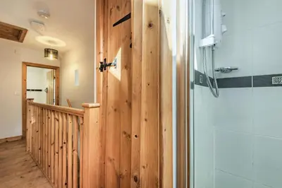 a bathroom with a shower and a wooden wall at Ty Capel Jeriwsalem in Trawsfynydd
