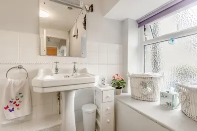 a white bathroom with a sink and a window at Penty in Dolgellau