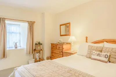 a bedroom with a bed and a dresser and a window at Penty in Dolgellau