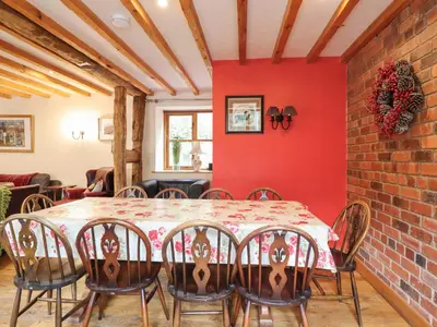 a dining room with a red wall and a table and chairs at Ysgubor Pwlliago in Pennant-Melangell