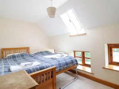 a bedroom with a bed and two windows at Ysgubor Pwlliago in Pennant-Melangell