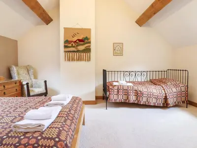 a bedroom with two beds and a chair at Ysgubor Pwlliago in Pennant-Melangell