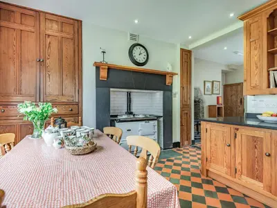 a kitchen with a table and a clock on the wall at Pensarn Hall in Llanbedr