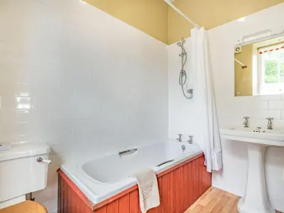 a white bathroom with a tub and a sink at Pensarn Hall in Llanbedr
