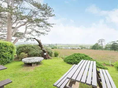a bench sitting in the grass with a field at Pensarn Hall in Llanbedr