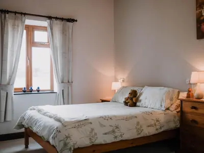 a teddy bear sitting on a bed in a bedroom at Stargazer's Field House in Clifford