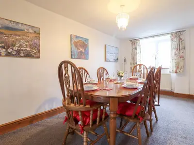 a dining room with a wooden table and chairs at Bryn Re in Trawsfynydd