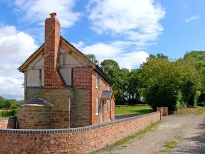 an old brick house with a brick wall at Point Cottage in Blakemere