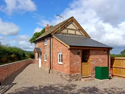 a brick house with a door on a gravel driveway at Point Cottage in Blakemere