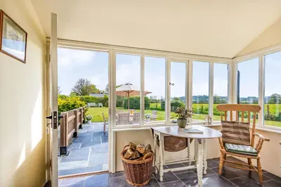 a conservatory with a table and chairs and a view at 2 Siluria Cottage in New Radnor