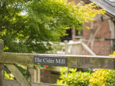 a sign that reads the cider mill on a wooden fence at The Cider Mill in Kings Pyon