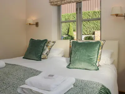 a bedroom with two beds with green pillows and a window at The Turnip House in Acton Scott